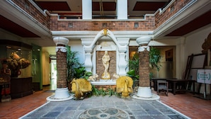 A lobby with a central statue, brick walls, and a tiled floor.