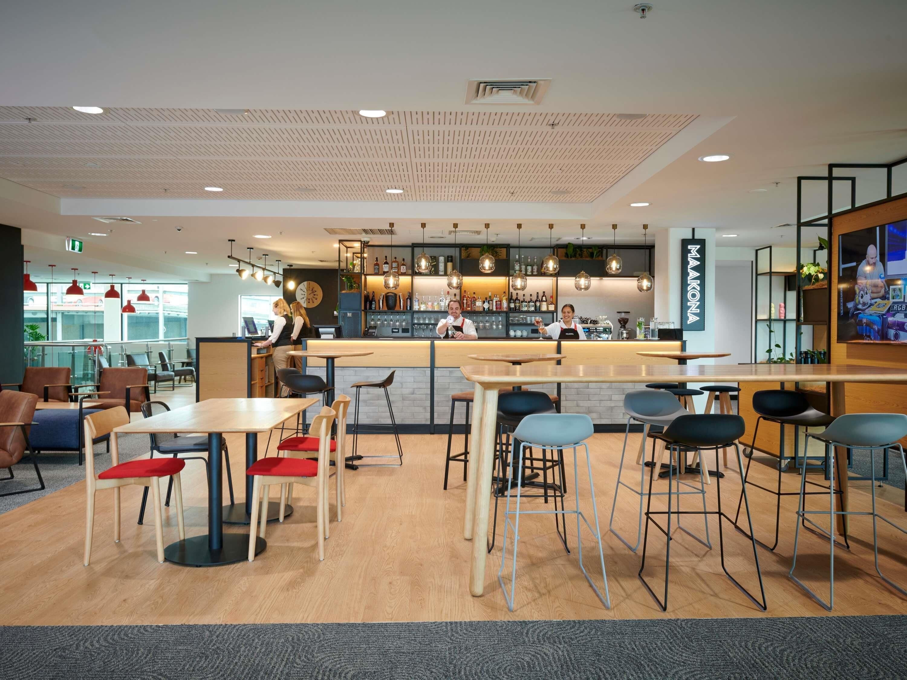 A modern bar area with a counter, stools, and a barista behind the counter.