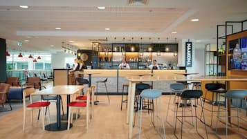 A modern bar area with a counter, stools, and a barista behind the counter.