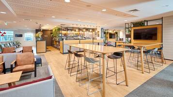 Zona de bar moderna con techo de madera, disposición de asientos y una pantalla grande.