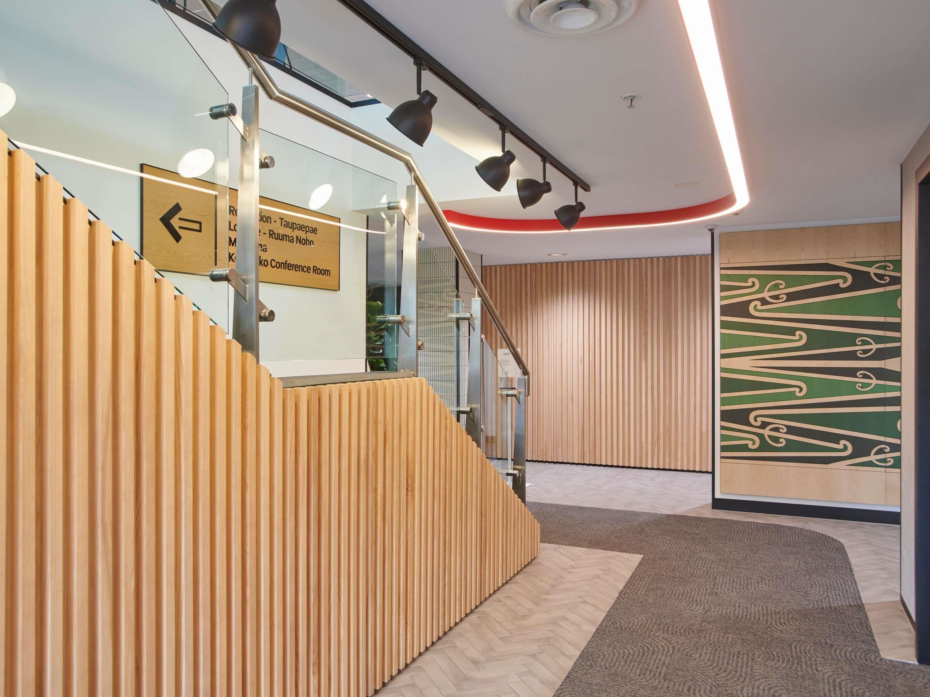 A modern interior with a wooden sloped wall, a glass staircase, and a conference room sign.