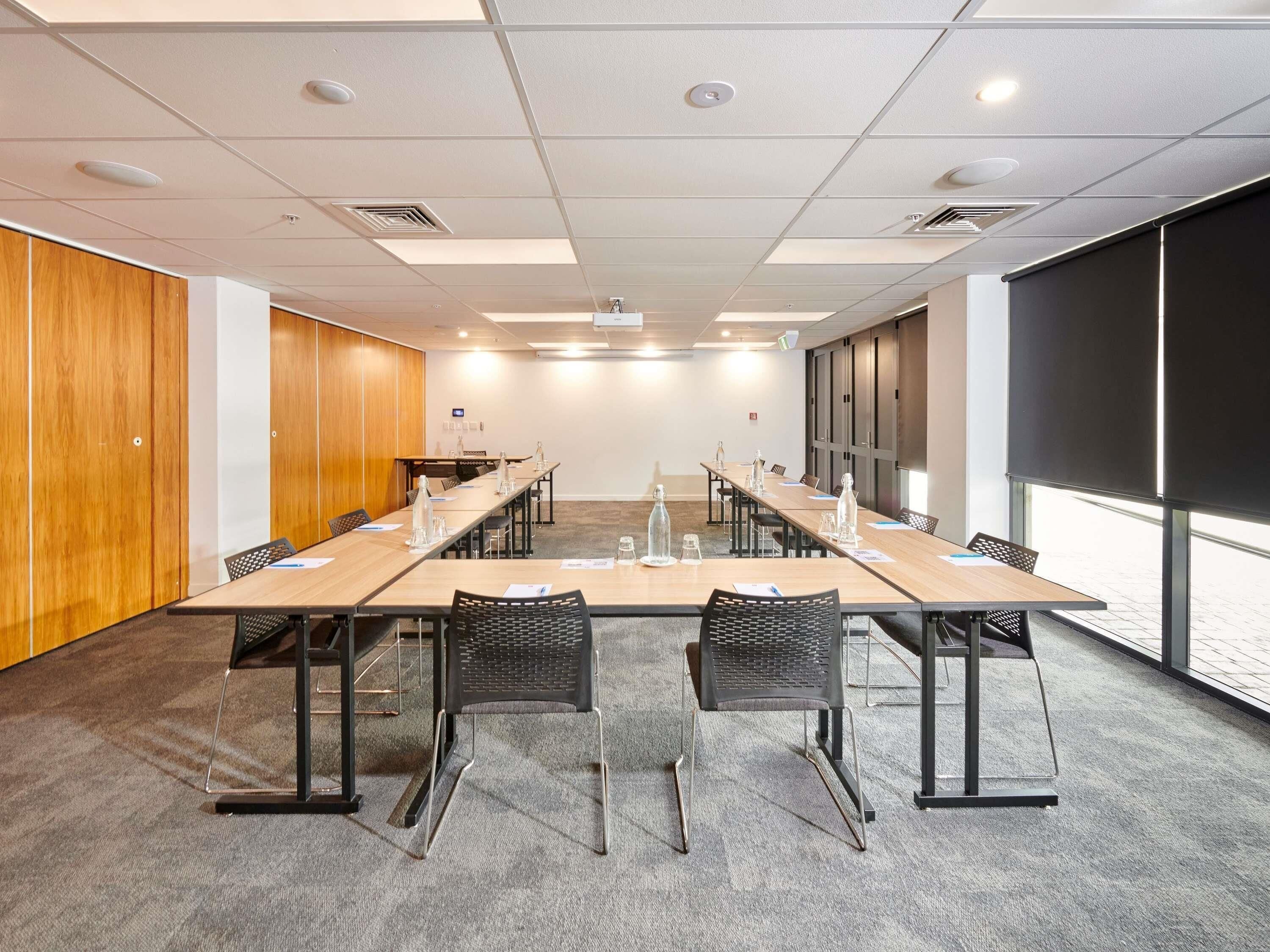 A conference room with a long table, chairs, and a projector screen.