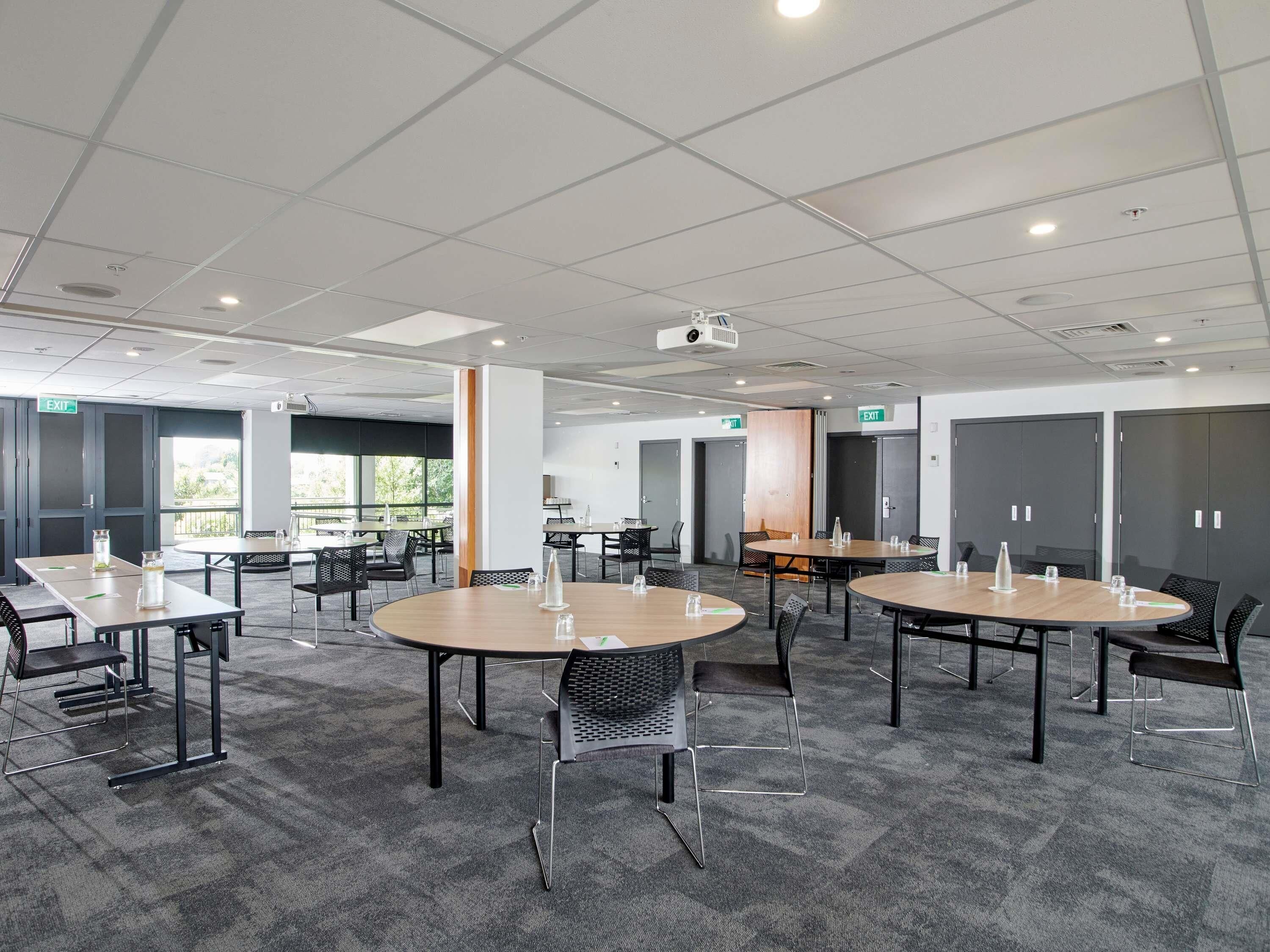 A conference room with round tables, chairs, and a projector.