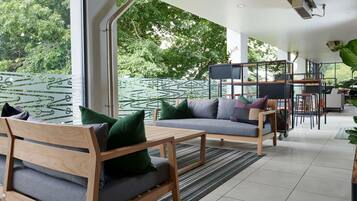 A modern outdoor living area with wooden furniture, a sofa, and a dining setup.