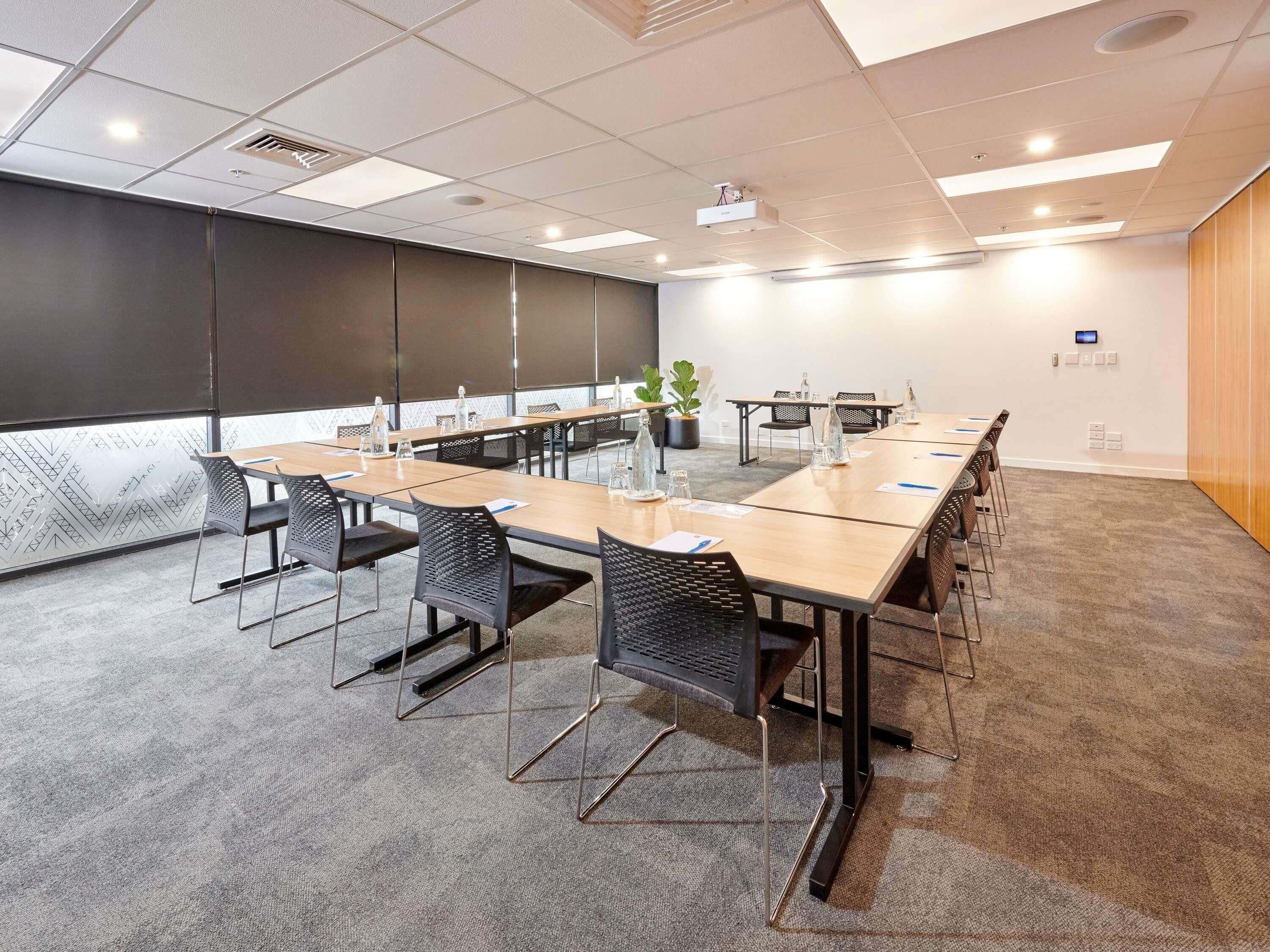 A conference room with a long table, chairs, a projector, and a plant.