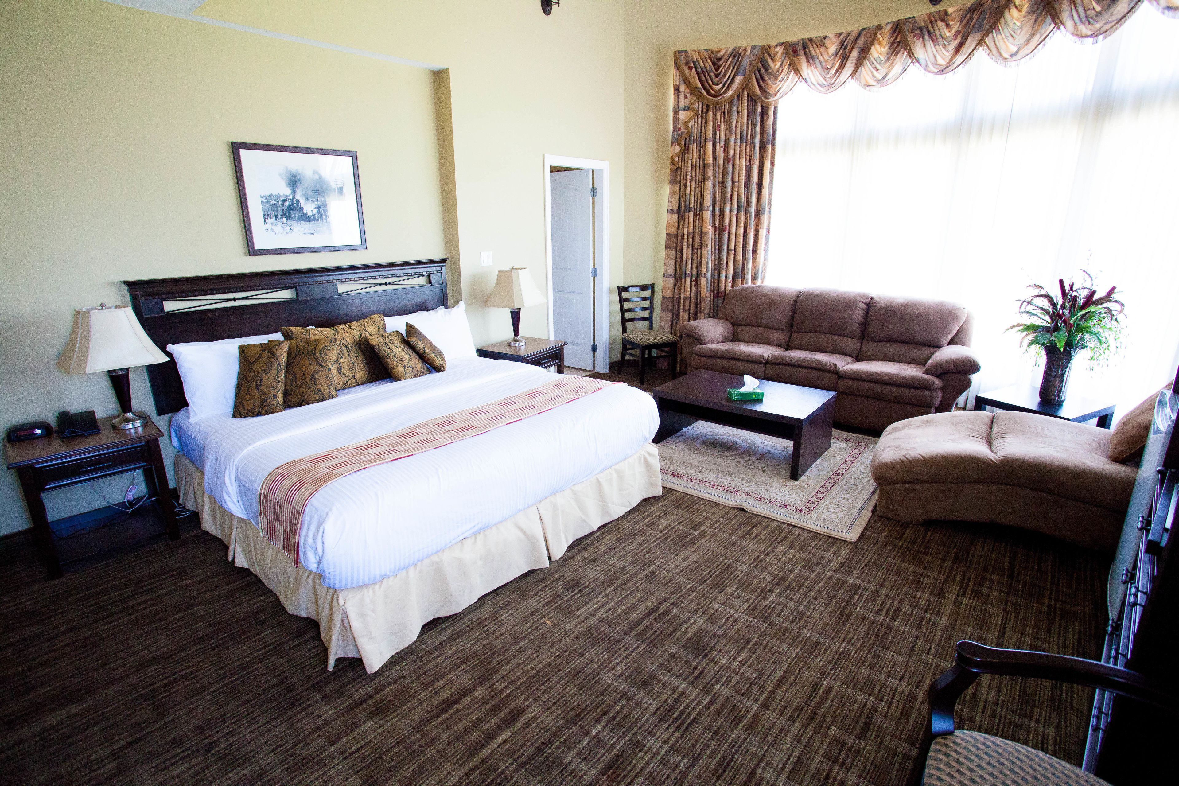 Una habitación de hotel con una cama, un sofá, una mesa de centro y una silla.