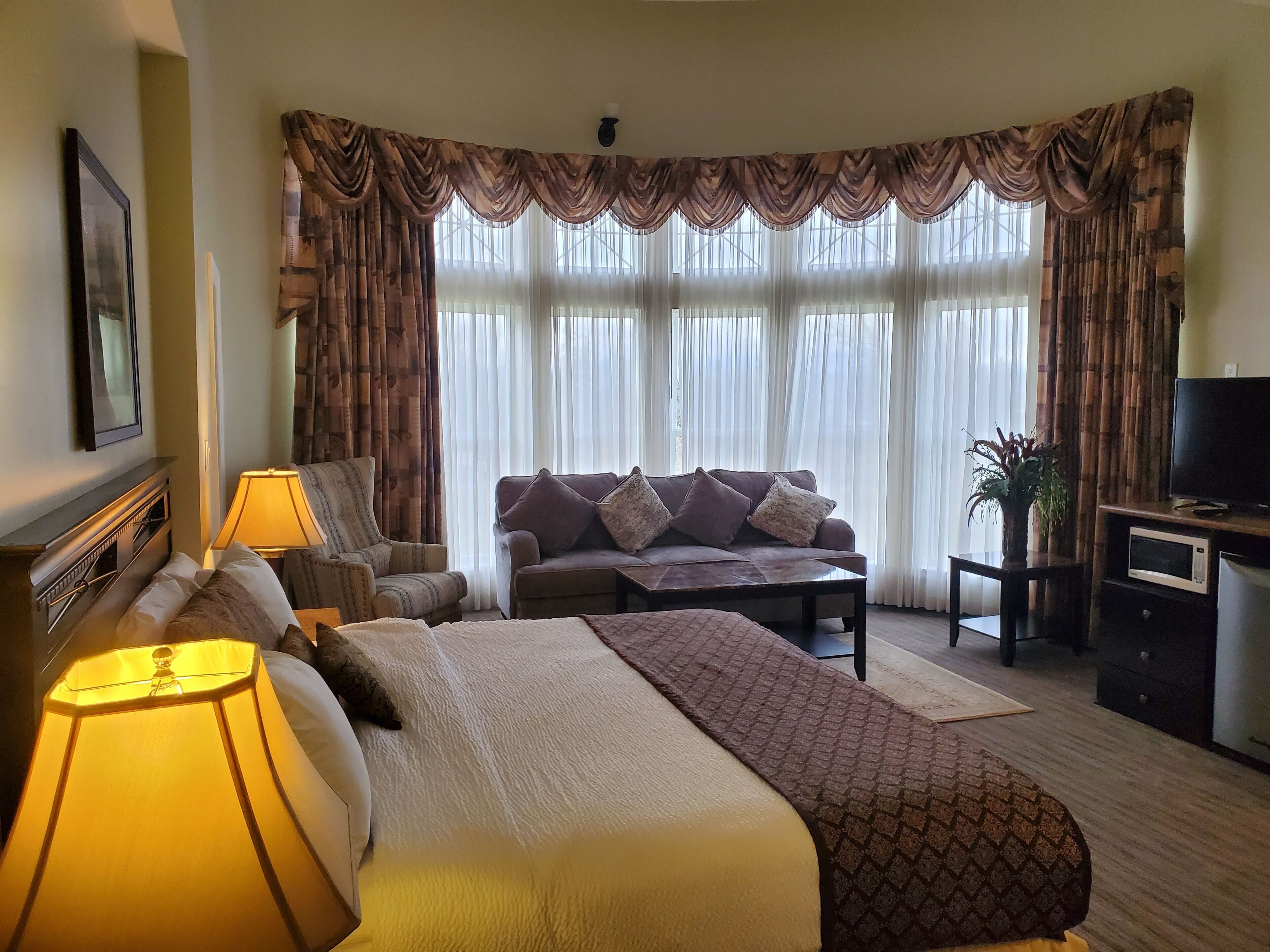 Una habitación de hotel con cama, sofá, televisión y escritorio.