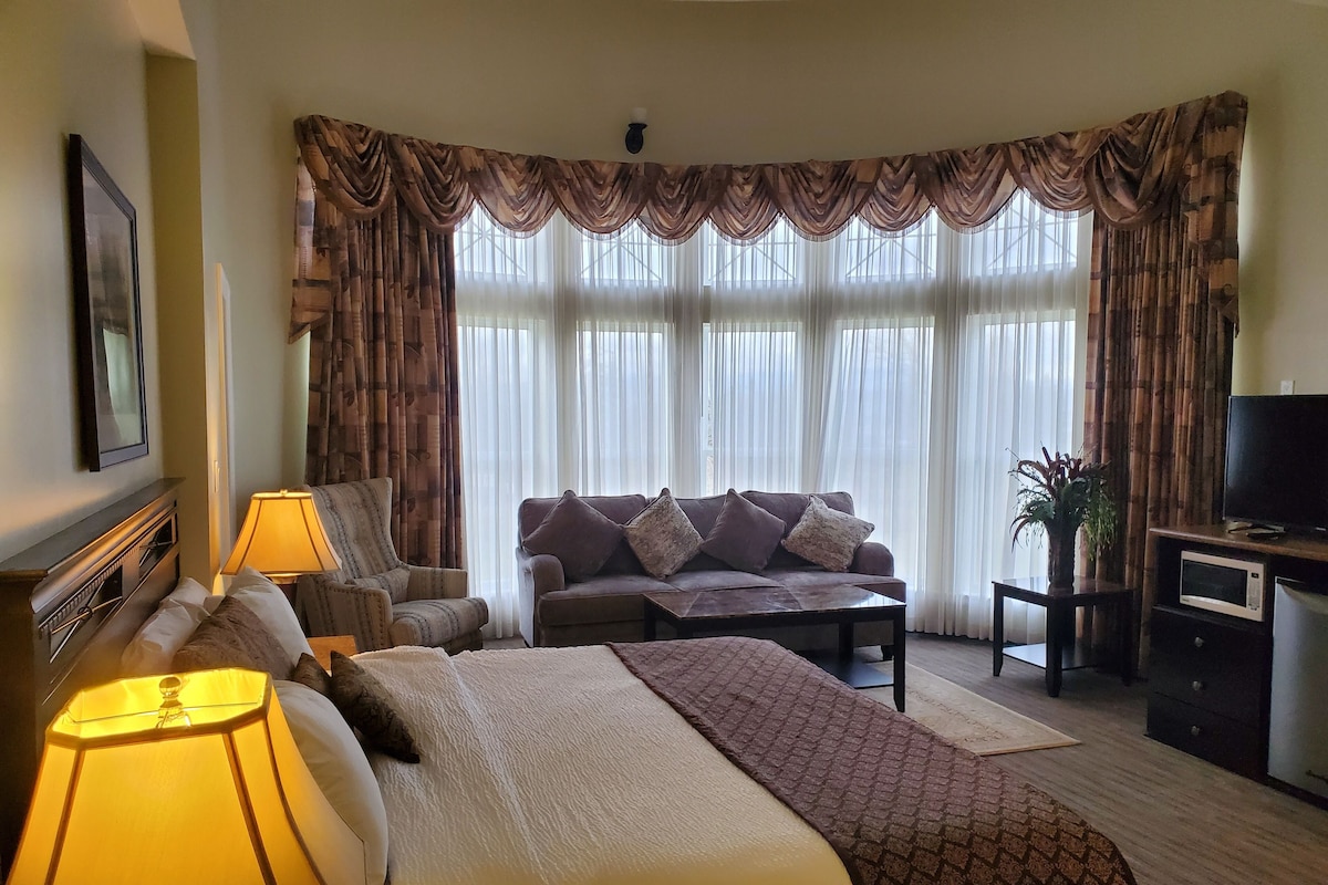 Una habitación de hotel con cama, sofá, televisión y escritorio.