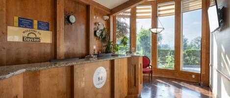A reception area with wooden paneling, a reception desk, a clock, and a sign welcoming guests to Days Inn.