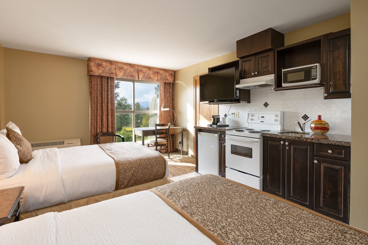 Une chambre d’hôtel avec deux lits, une kitchenette, une télévision et une vue sur l’extérieur.