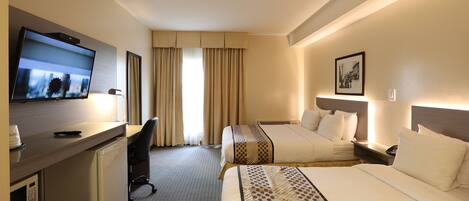 Habitación de hotel con televisión, escritorio, dos camas, microondas y ventana con cortinas.