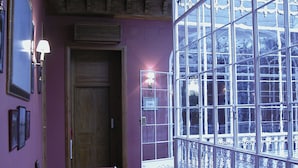 Una habitación con un gran ventanal, techo de madera y un sofá rosa.