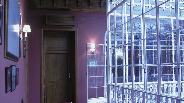 Una habitación con un gran ventanal, techo de madera y un sofá rosa.