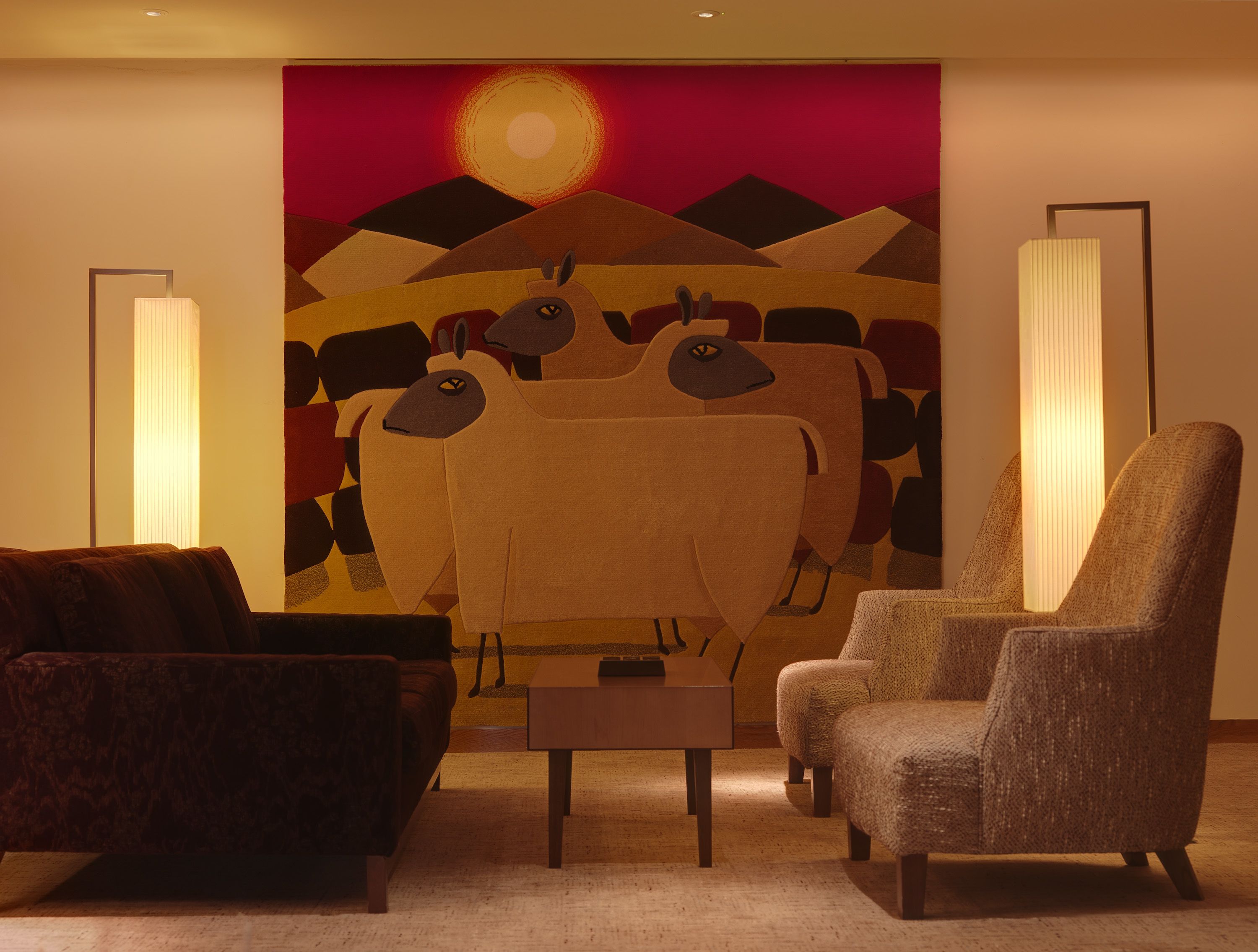 Una sala de estar con un cuadro abstracto grande, un sofá, un sillón y dos lámparas de pie.