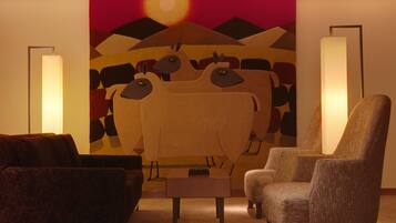 Una sala de estar con un cuadro abstracto grande, un sofá, un sillón y dos lámparas de pie.