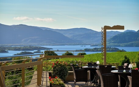 Una terraza con mobiliario de mimbre, vista a un lago y un letrero que dice 'OAKHADOE'.