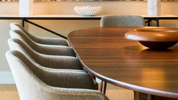 A dining area with a wooden table, grey upholstered chairs, and a large abstract painting on the wall.