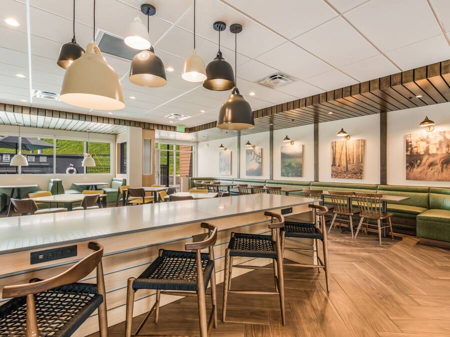 Een modern restaurant met een lange toonbank, verschillende zithoeken en hanglampen.