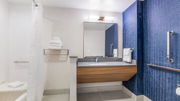 A modern bathroom with a wooden vanity, a large mirror, and a blue textured wall.