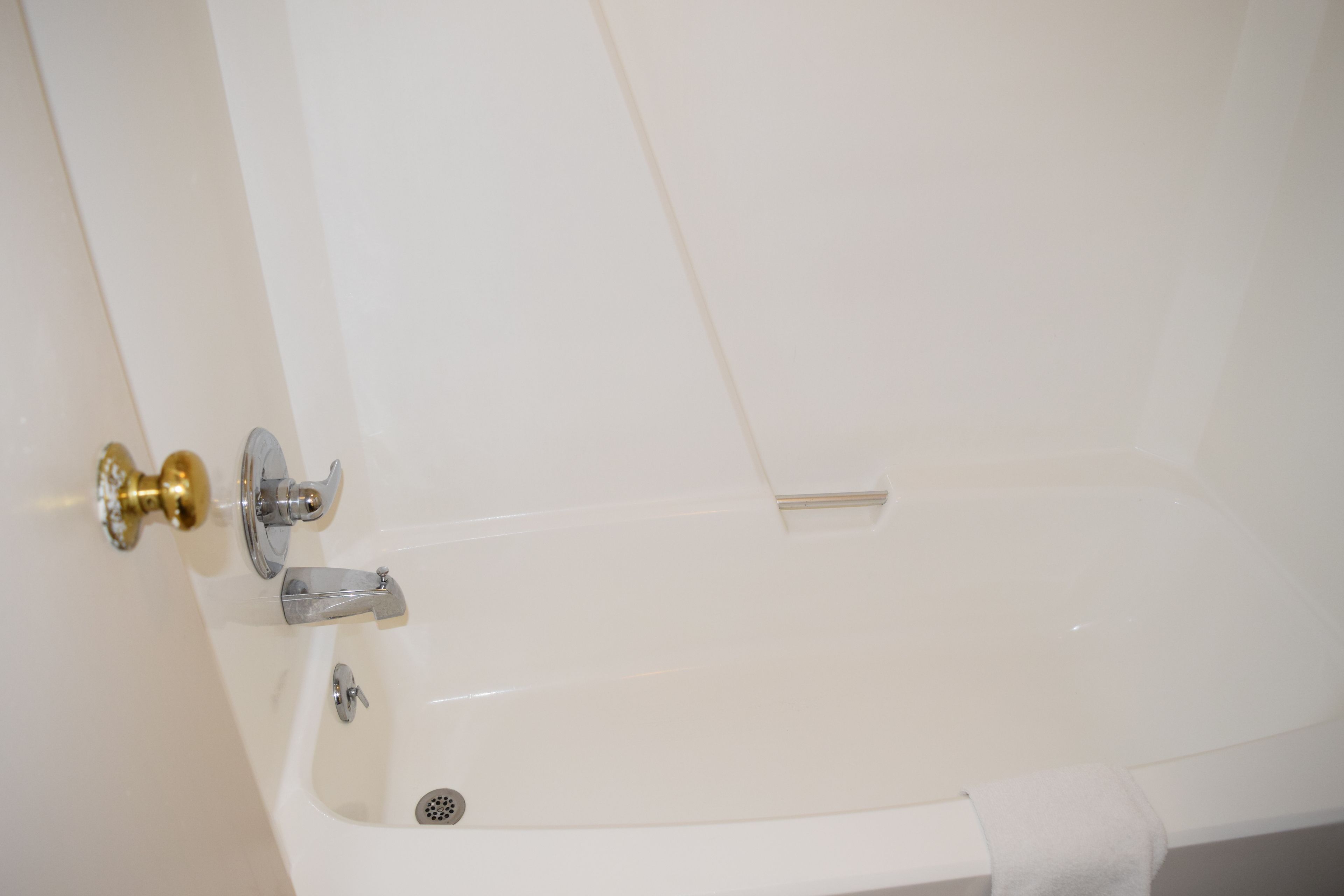 Eine weiße Badewanne mit goldener Armatur und einem Handtuch an der Seite.