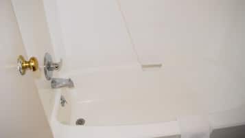 Eine weiße Badewanne mit goldener Armatur und einem Handtuch an der Seite.