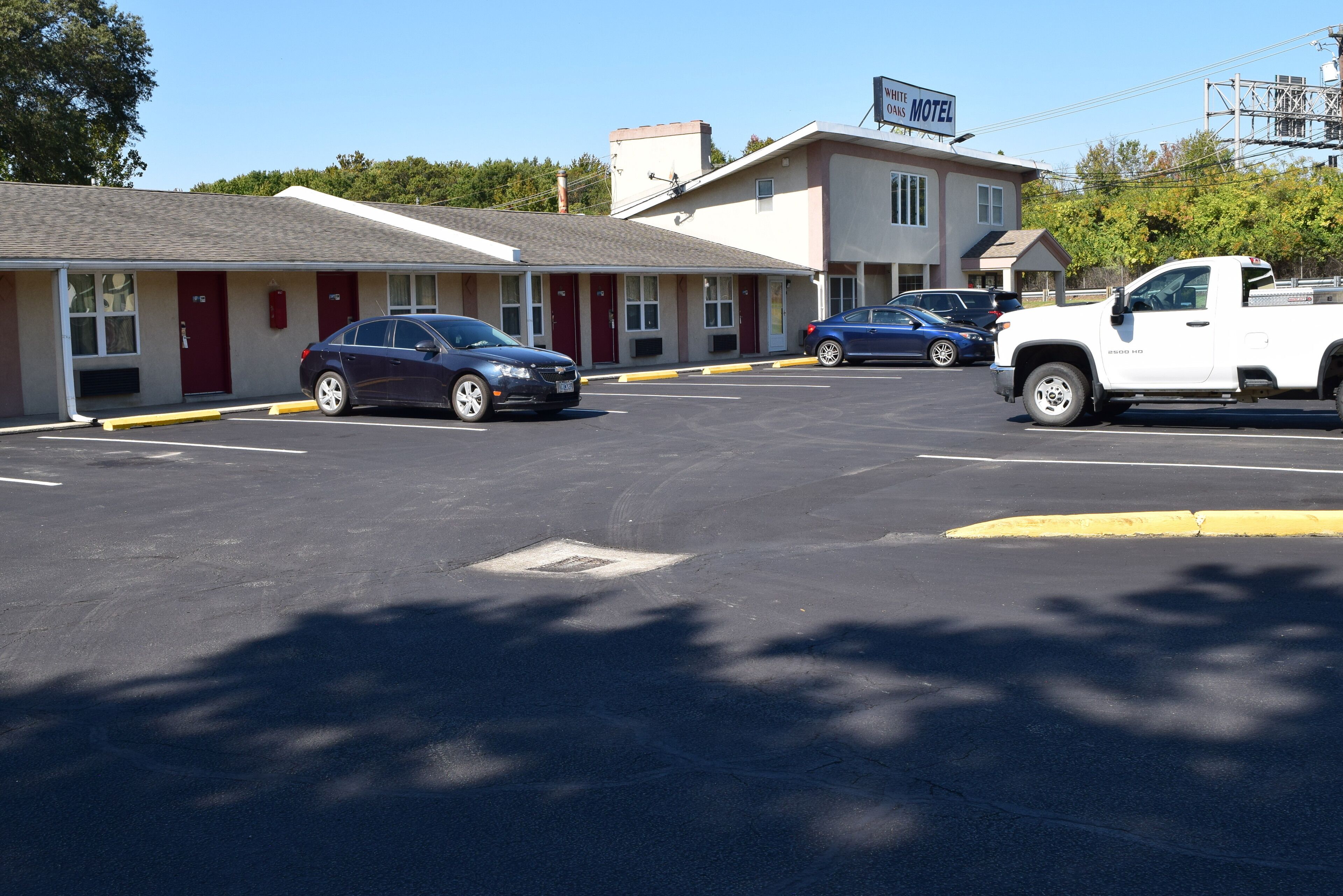 A motel with a parking lot, a blue car, and a white truck.