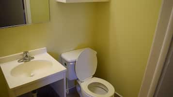 Un baño con lavamanos, inodoro y espejo blancos.