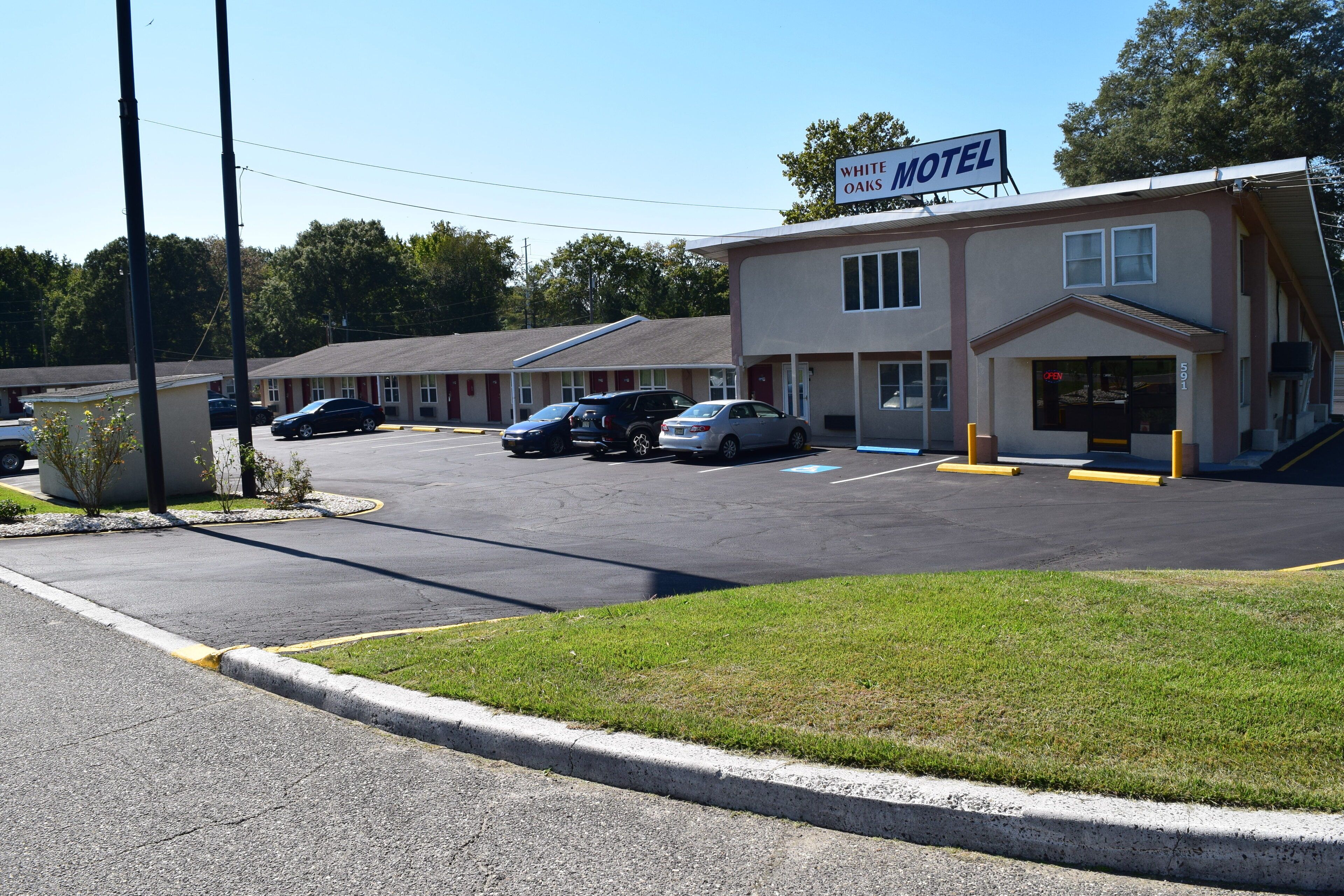 A motel with a sign reading "White Oaks Motel" and a parking lot with several cars.