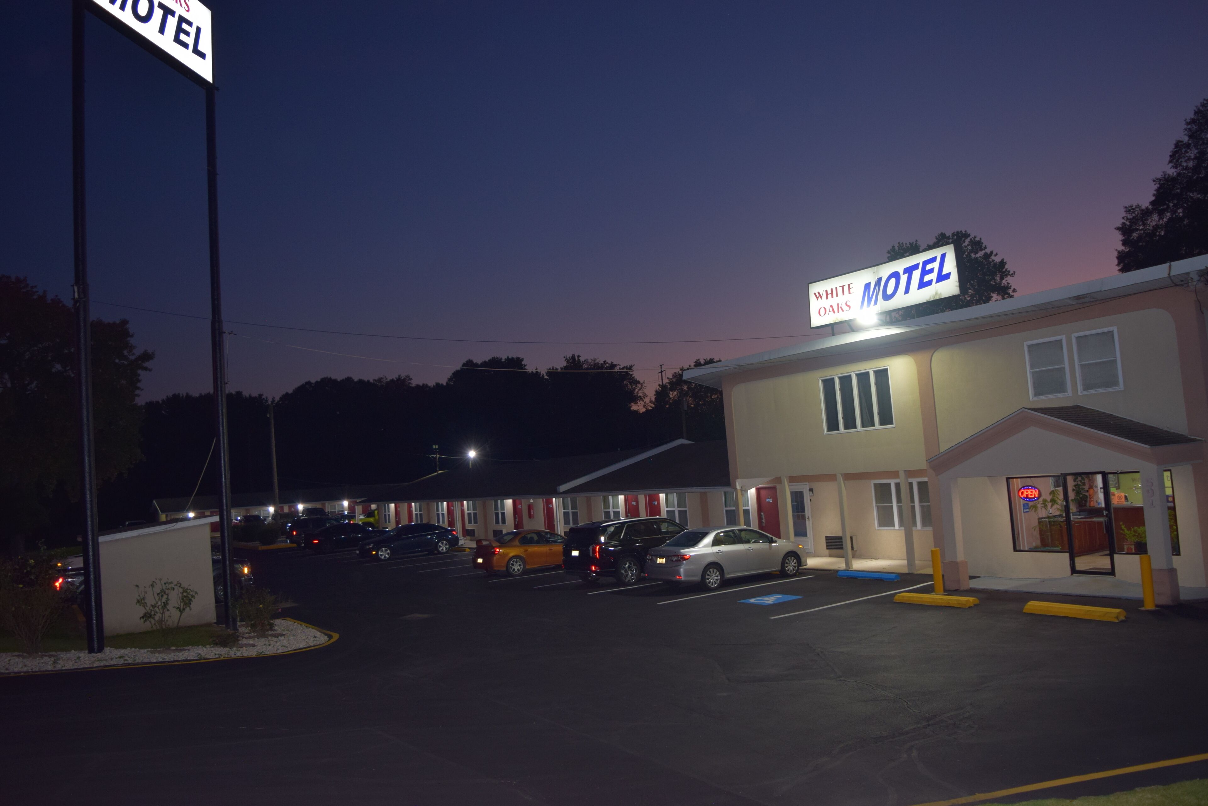 A motel with a sign reading "White Oaks Motel" and a parking lot with several cars.