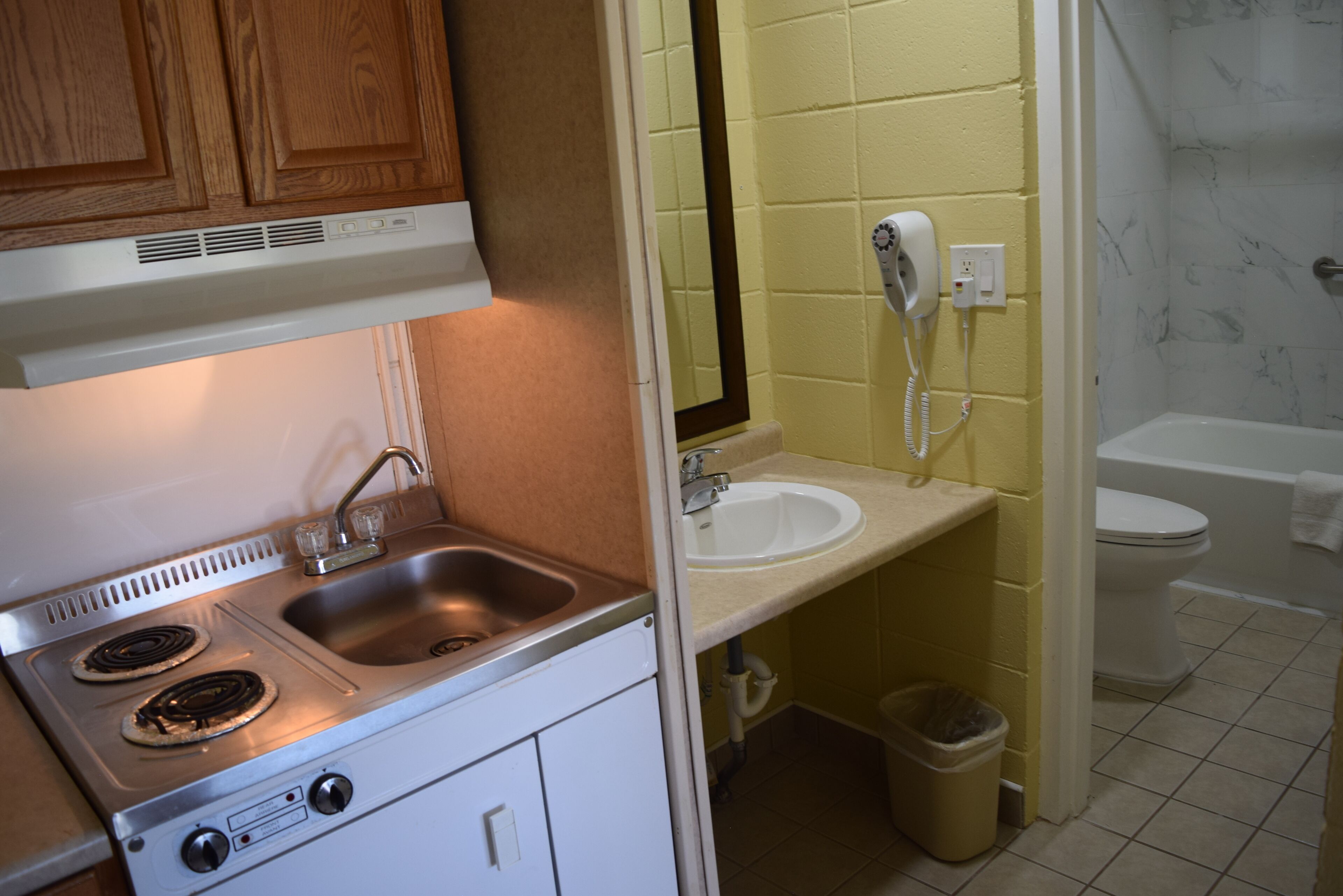 A kitchen with a stove, sink, and wooden cabinets.
