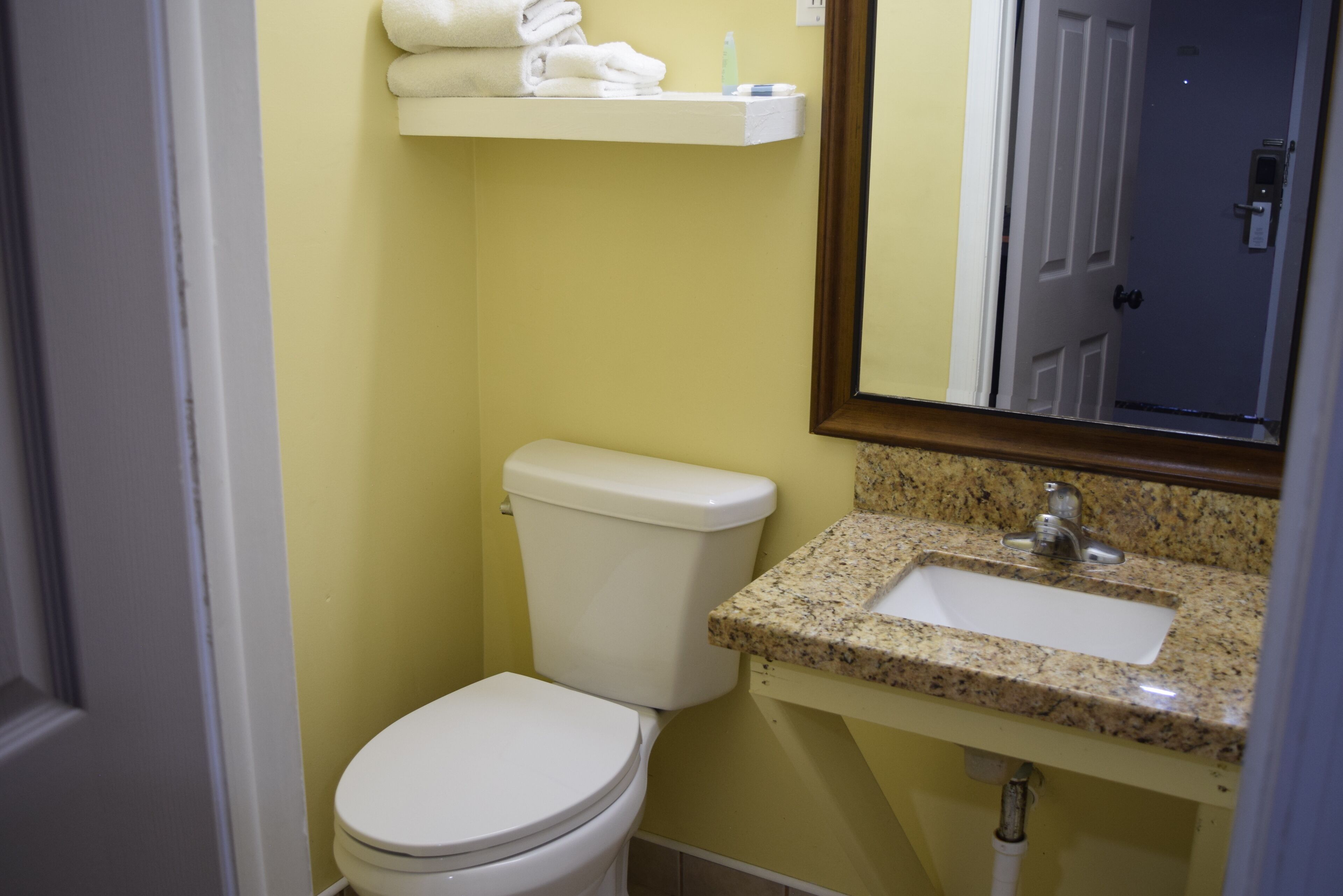 A bathroom with a toilet, sink, and mirror.