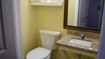 A bathroom with a toilet, sink, and mirror.