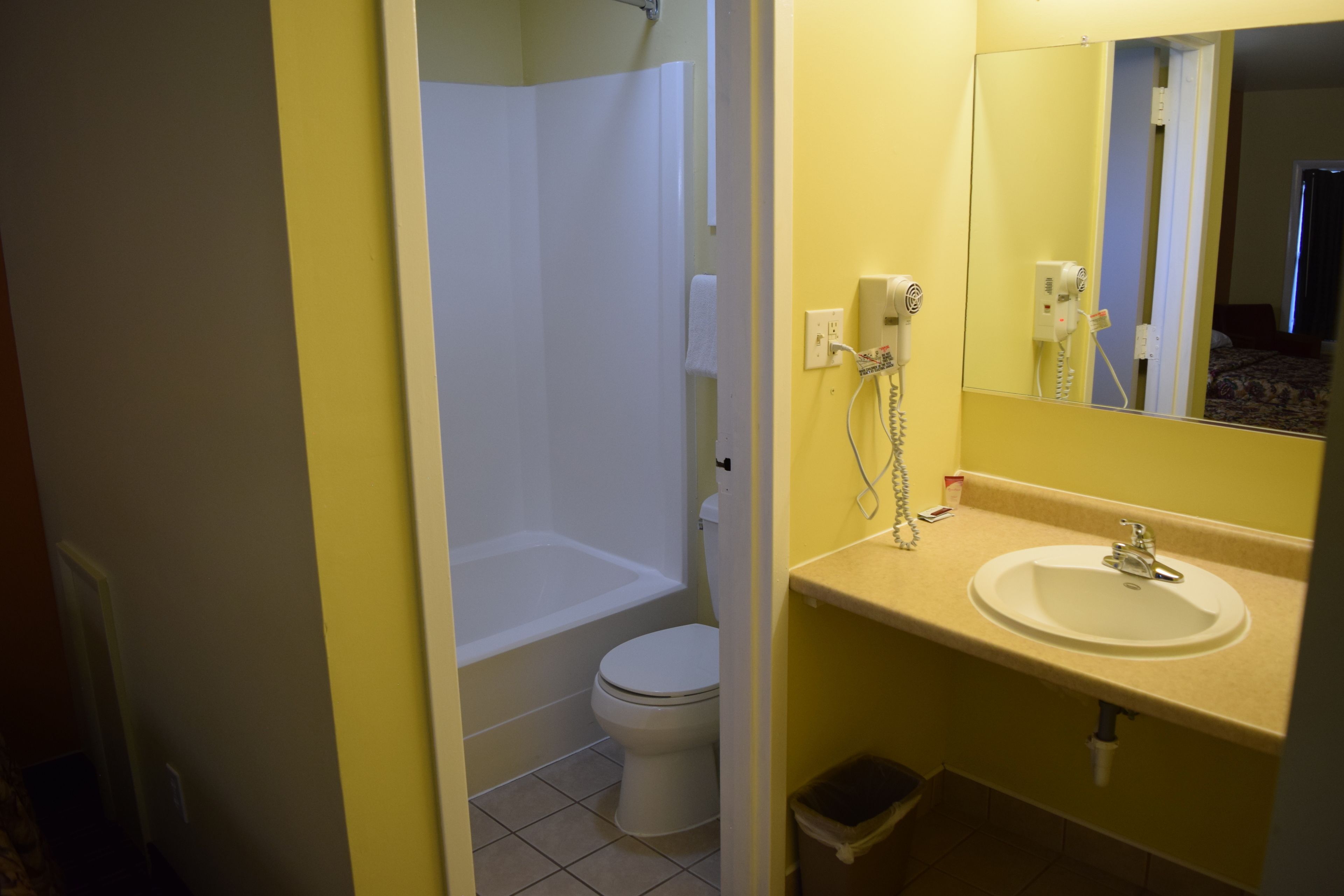 A bathroom with a white toilet, a bathtub, and a sink with a mirror above it.