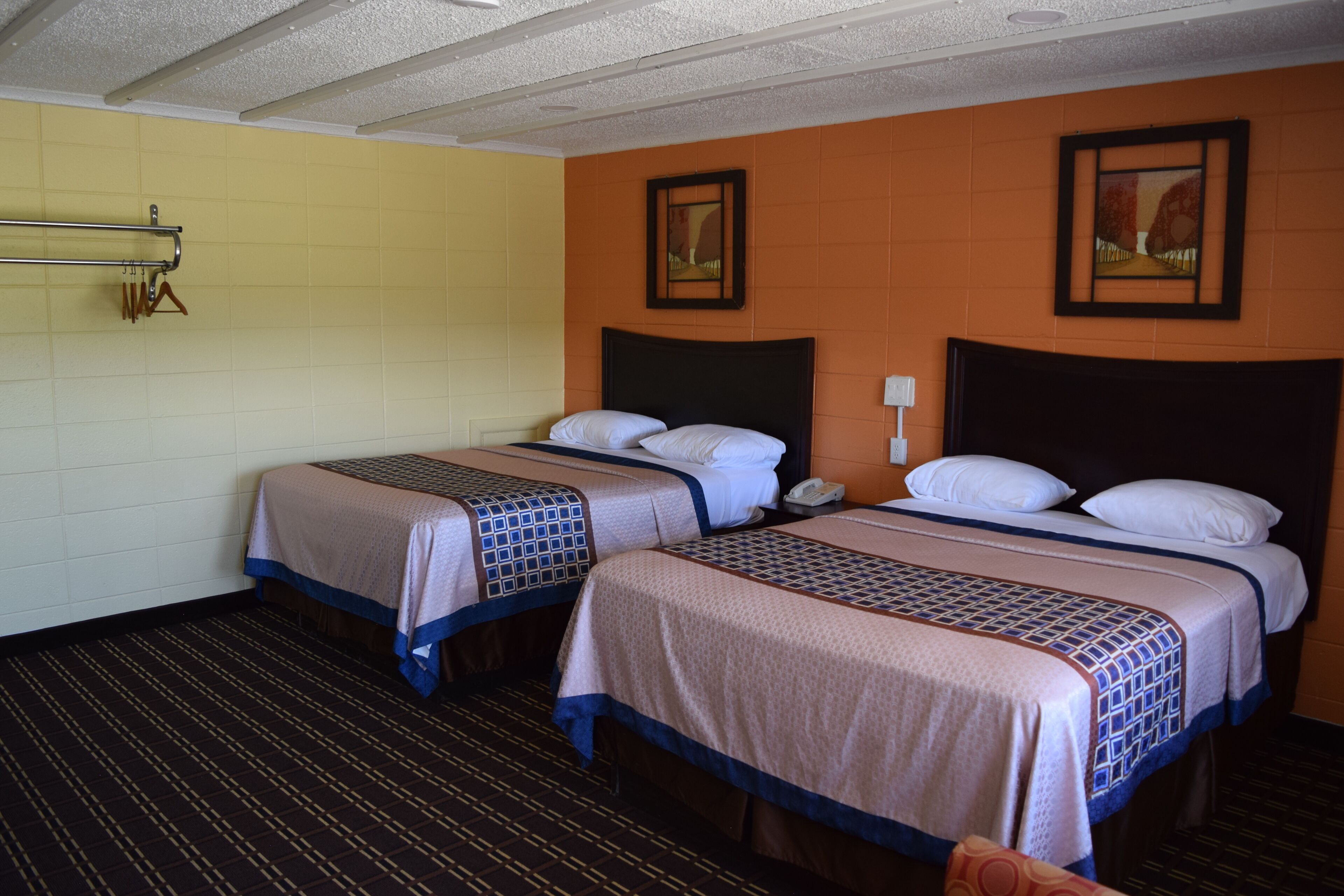 Habitación de hotel con dos camas, un teléfono y un perchero en la pared.