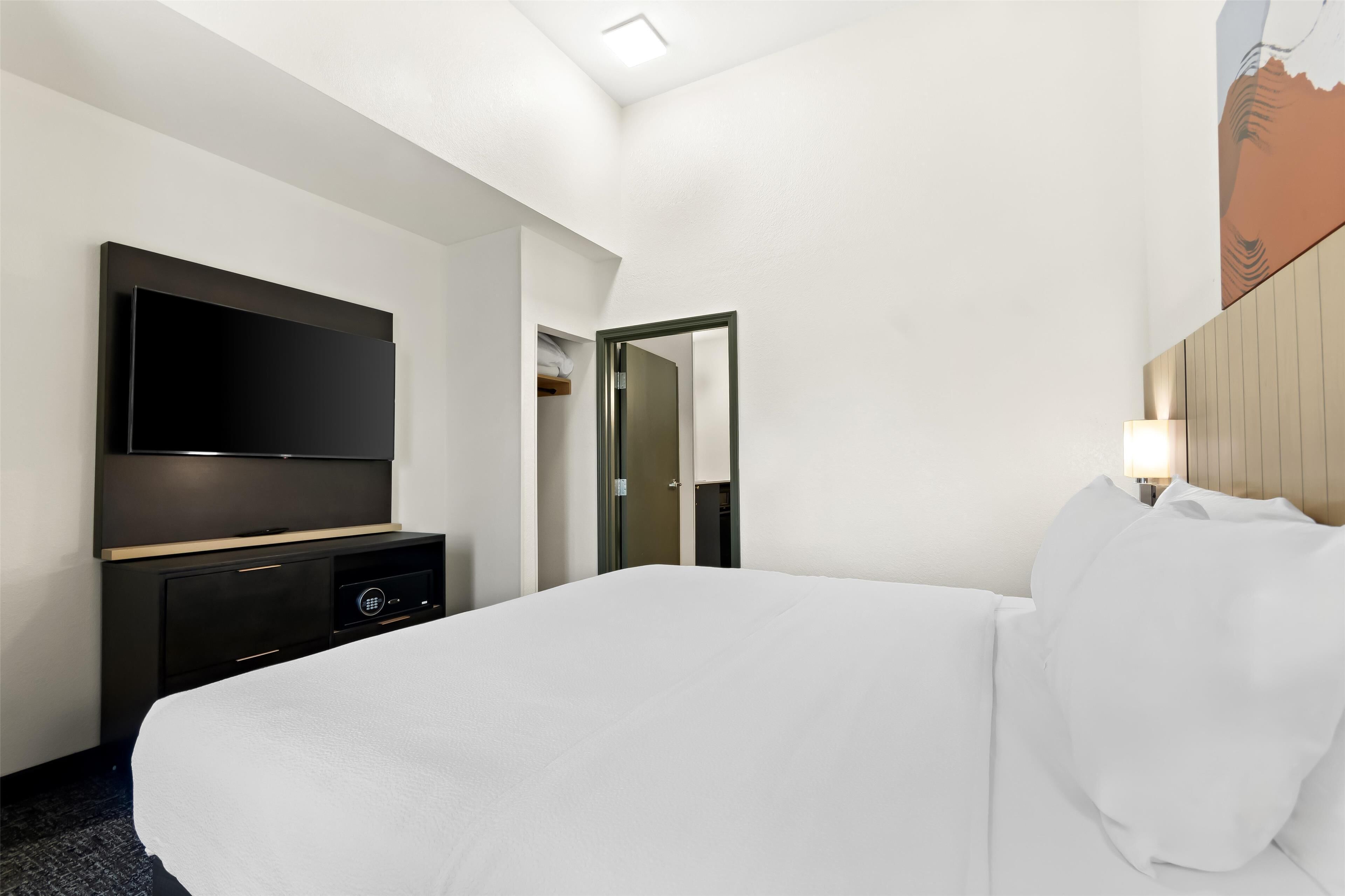 A hotel room with a large bed, a flat-screen TV, a dresser, and a mirror.