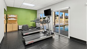 A fitness center with treadmills, a mirrored wall, a television, and a pool view. - Spark by Hilton Panama City Beach (Panama City Beach)