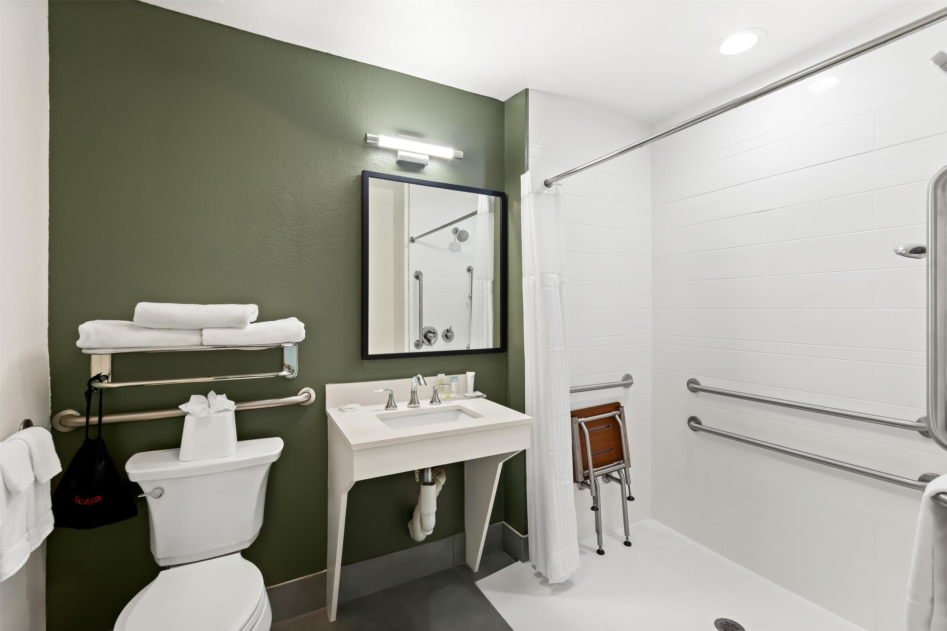 A modern bathroom with a white sink, toilet, and shower area.
