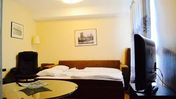 Una habitación de hotel con una cama, una silla, un escritorio con computadora y televisión.