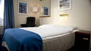 A hotel room with a bed, a chair, a nightstand, and two wall-mounted lamps.