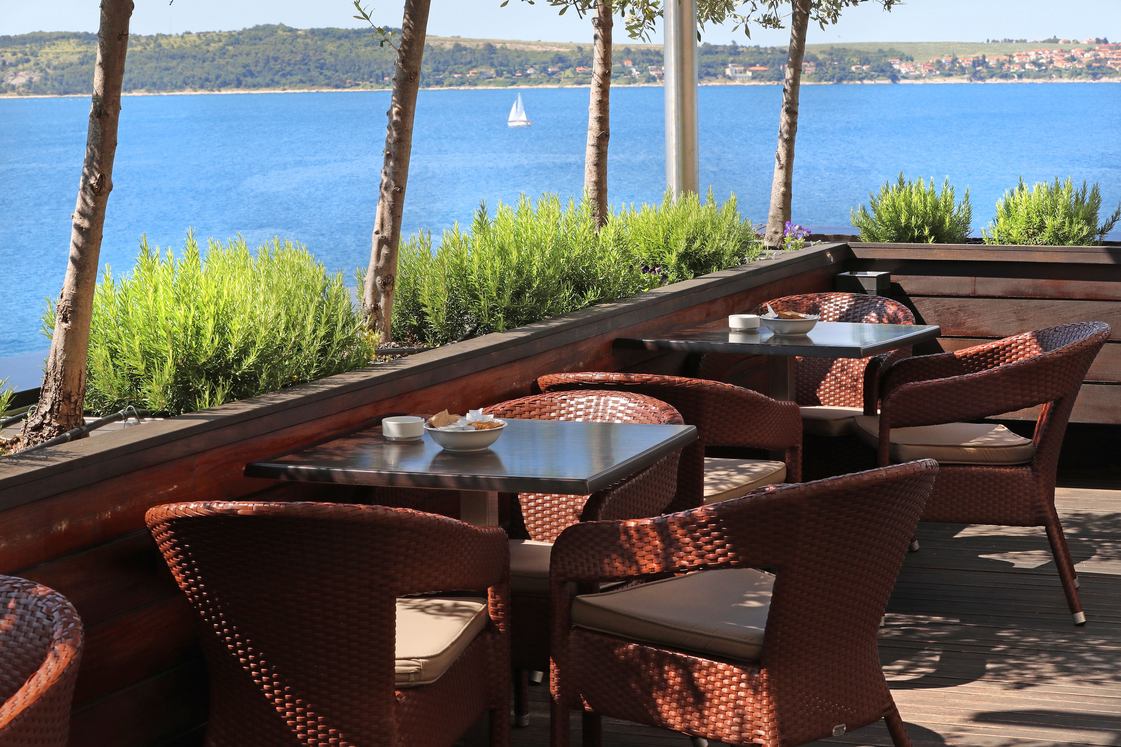 An outdoor seating area with wicker furniture and a view of the sea.