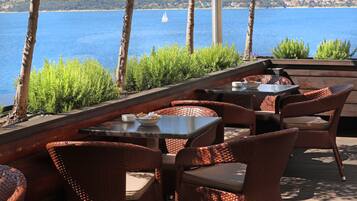 An outdoor seating area with wicker furniture and a view of the sea.