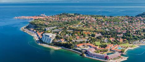 An aerial view of a coastal town with a prominent waterfront, a central building complex, and surrounding residential areas.