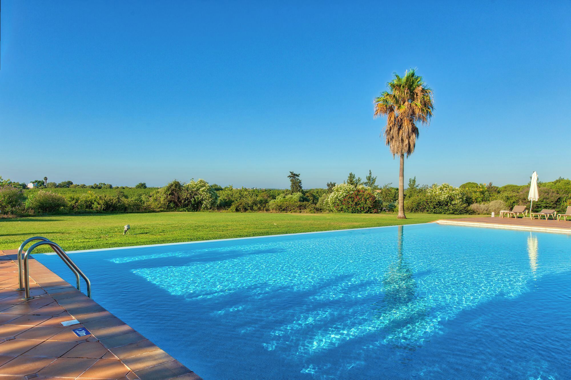 حمّام سباحة خارجي، مظلات على حمّام السباحة، مقاعد للتشمس