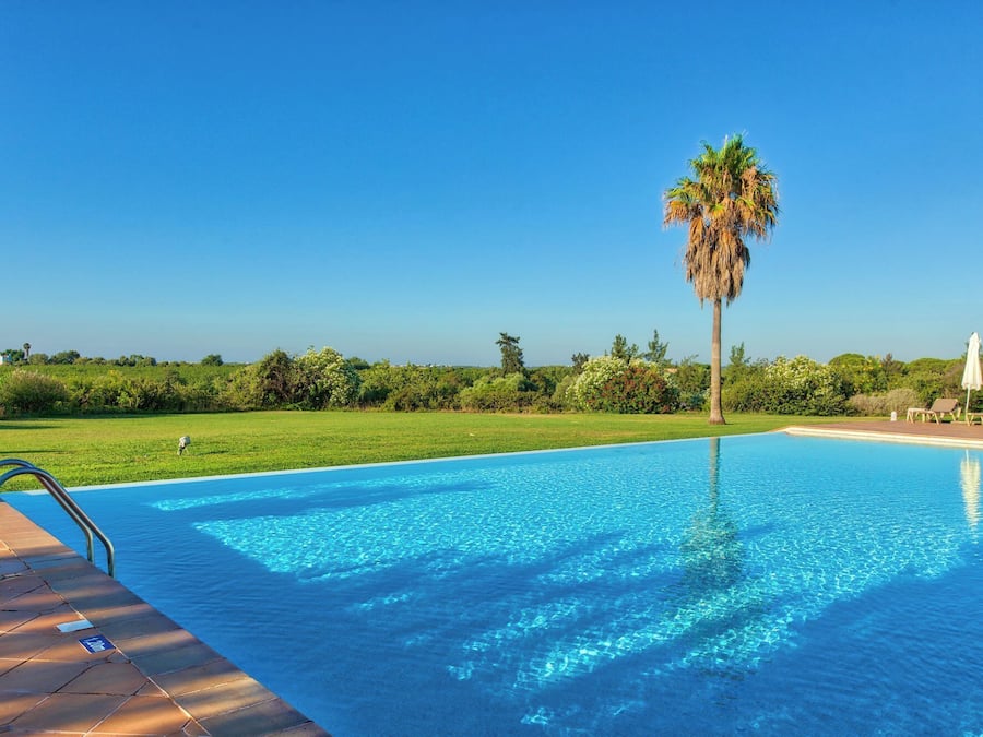 Una piscina al aire libre, sombrillas, tumbonas