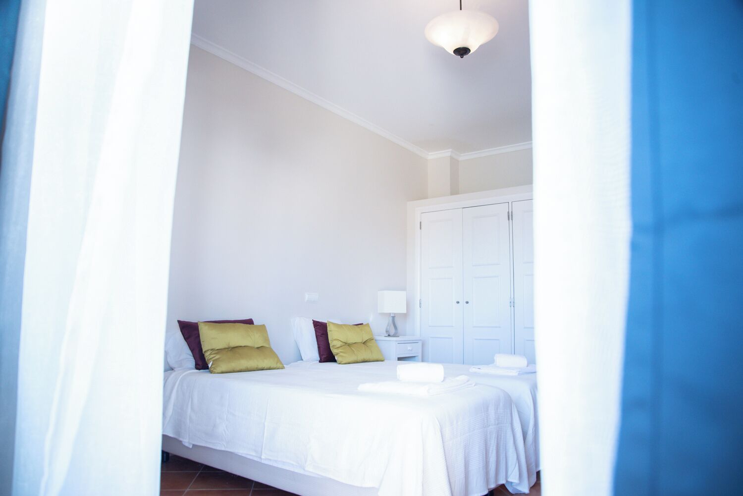 A bedroom with a bed, pillows, a nightstand, and a wardrobe.