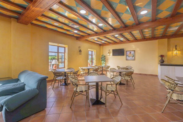 A spacious dining area with high ceilings, wooden beams, and tiled flooring.