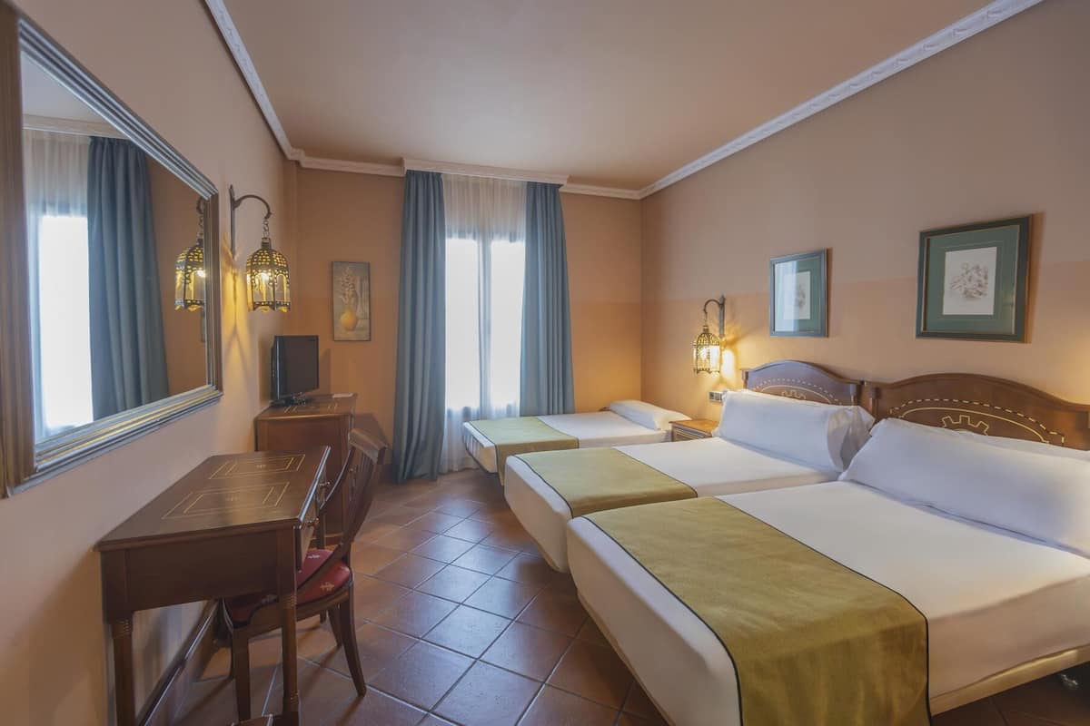 A hotel room with two beds, a desk, a chair, and a large mirror.