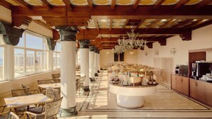Un hall d’hôtel spacieux, doté de hauts plafonds, de grandes fenêtres et d’un bar central.