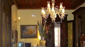 A spacious living room with a wooden floor, a chandelier, a sofa, a desk with a computer, and a painting on the wall. - Hotel Aurora (Syracuse)