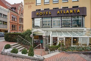 Un hotel llamado ATLANTA con una fachada moderna, ventanas grandes y una entrada de vidrio.